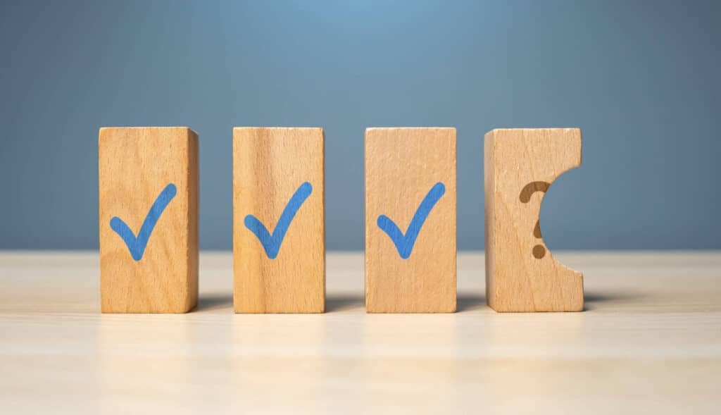 A set of four wooden blocks the first 3 have a blue tick while the fourth is broken and has a question mark